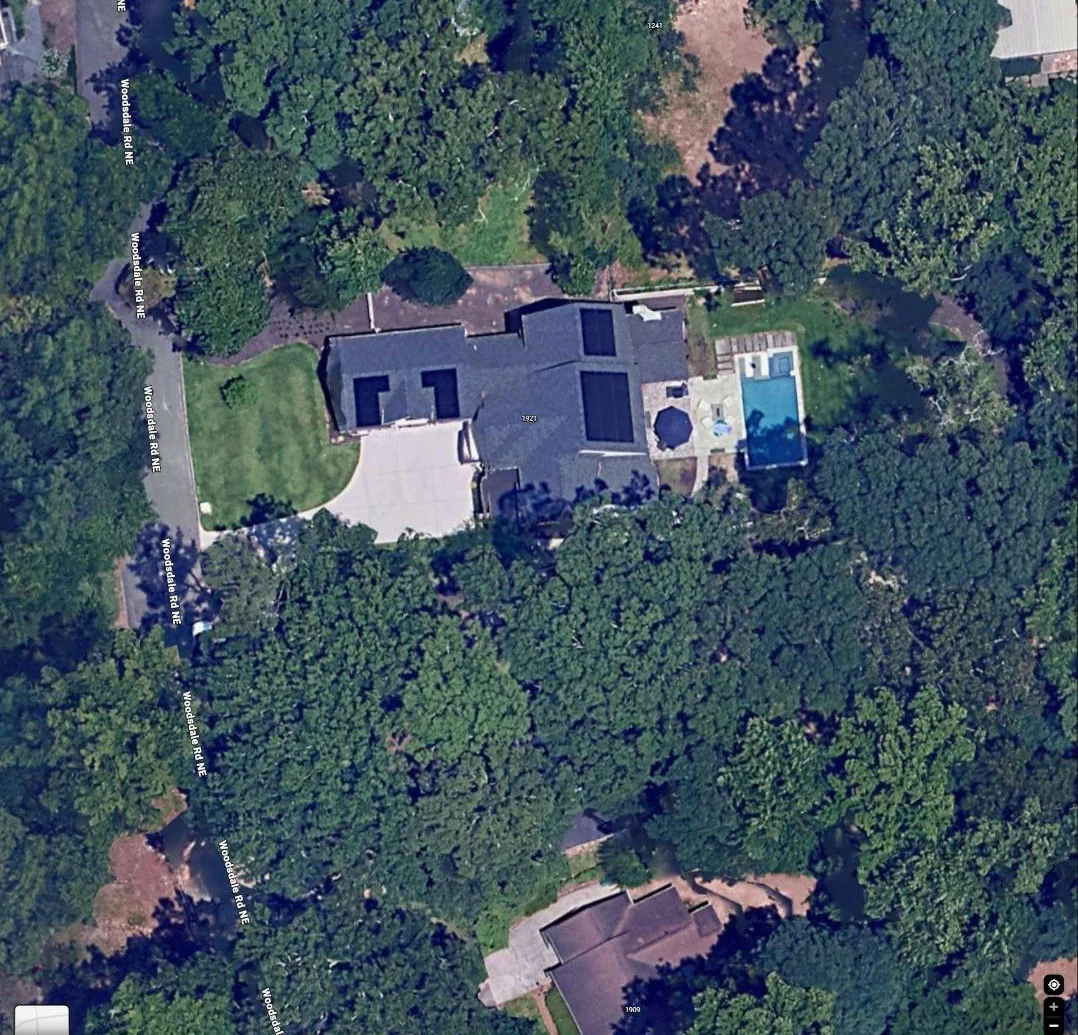 Aerial view of a residential rooftop with solar panel arrays across multiple roof sections and an adjacent pool