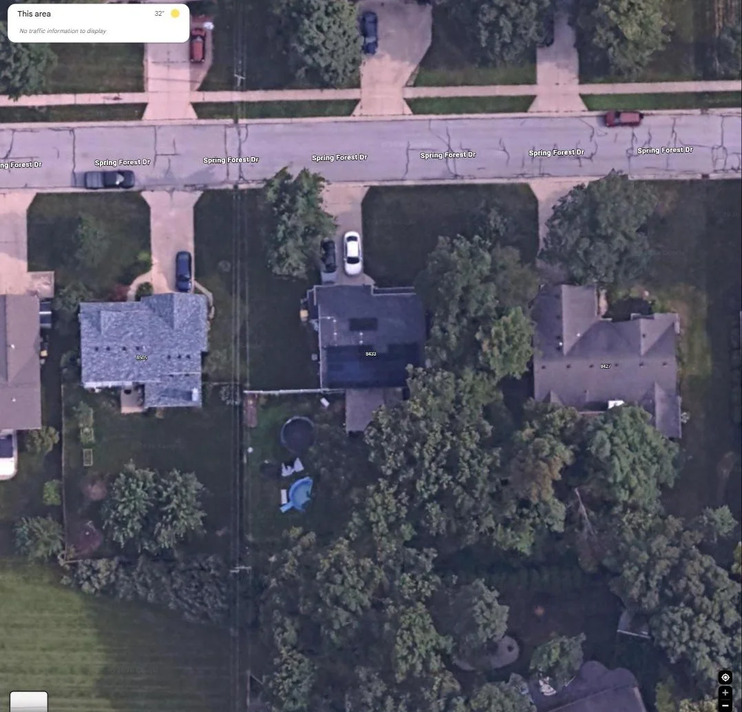 Aerial view of a suburban residential rooftop with a solar array, among neighboring homes