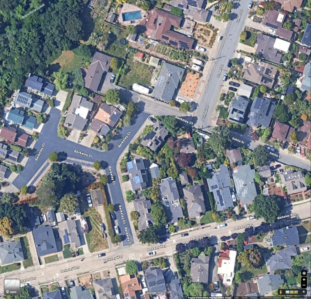 Aerial view of a suburban residential rooftop with a solar array, on a cul-de-sac