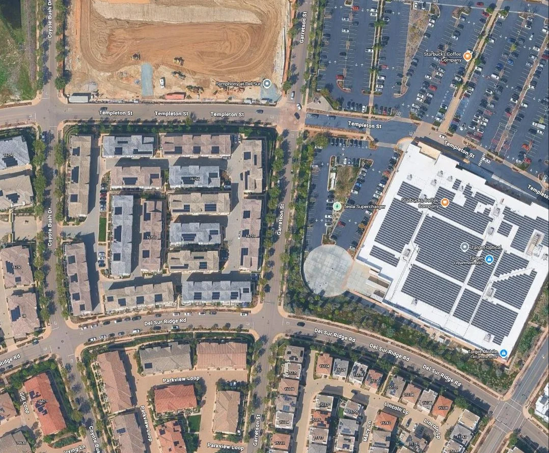 Satellite view of the helix single-tilt rooftop solar array covering a big-box retail store roof, with adjacent Tesla Supercharger site